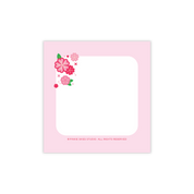 Pink square sticky note with floral design on a white background