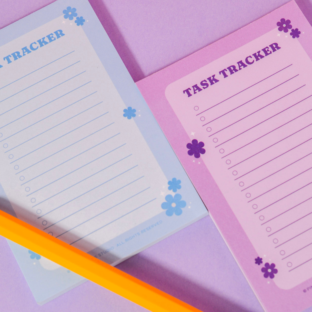Flat lay of Bloom Task Tracker Notepad by Pinkie Skies Studio, featuring colorful sections and organized layout for tasks.